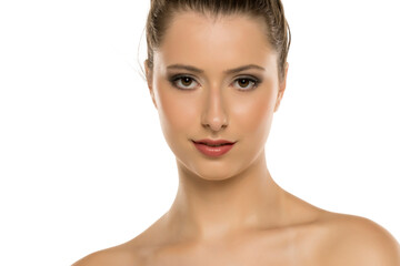 Fototapeta premium Studio shot of a young woman with brown hair, styled up, wearing makeup and smiling slightly, on white background.