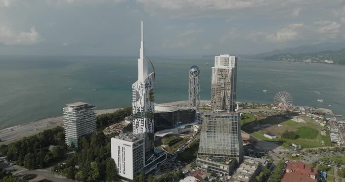 Aerial view of the Alphabet Tower, Radisson Blu Hotel, Ferris wheel, and the contrasting urban architecture against the sea, Batumi, Adjara, Georgia.
