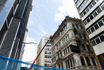 View of an old building being demolished by workers on a crane. Salvador, Bahia.