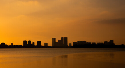 Fototapeta premium Golden sunset over the lake, silhouetted friends watching the glowing horizon in peaceful harmony.