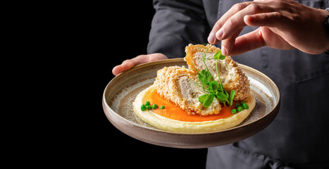 chef hands with Breaded chicken roll with mashed potatoes and carrot puree on a plate. copy space