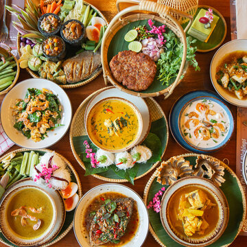 Traditional Thai Feast, A colorful spread of authentic Thai dishes beautifully arranged with fresh vegetables, curries, and side dishes, showcasing rich flavors and culture.