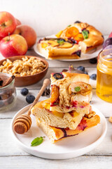 Tasty fruit dessert Focaccia. Sweet viral italian Focaccia open pie, with various seasonal autumn and summer fruits - plum, apple, figs, apricot, blueberry, peach and nuts, with spices and honey