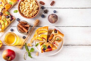 Tasty fruit dessert Focaccia. Sweet viral italian Focaccia open pie, with various seasonal autumn and summer fruits - plum, apple, figs, apricot, blueberry, peach and nuts, with spices and honey