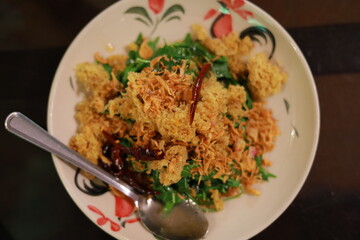 Yum Sa Dao Pla Duk Foo served with crispy catfish flakes, greens, fried shallots, and chilies at Baan Pueng Chom restaurant, Ari, Bangkok.