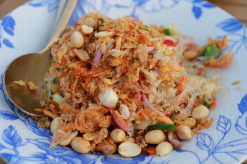 Thai glass noodle salad with fried shallots, peanuts, herbs, and vegetables served on floral plate at Supanniga Eating Room Tha Tien, Bangkok, Thailand.
