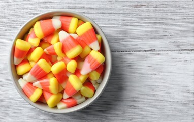 Bowl of colorful candy corn on rustic wooden surface