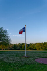 The Flag of Texas fluttering in the Evening light at the Parking area near to Creekfield Lake in Brazos Bend State Park in Texas.