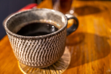 Coffee was served in delicate ceramic cup on wooden table in morning light