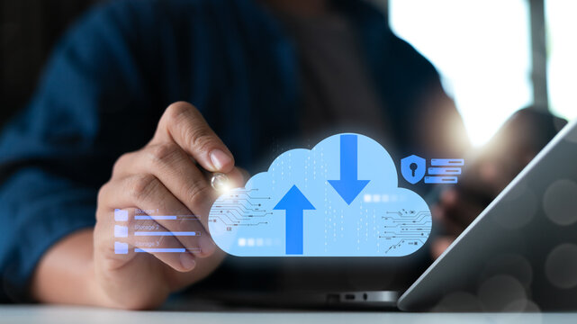 Close-up of a businessman using a laptop with hologram cloud computing upload and download icons. Concept of data storage, cybersecurity, online backup, secure file management, and digital technology. - Powered by Adobe