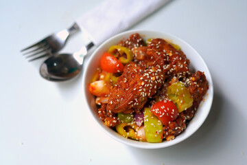 Hot and Flavorful Devil Chicken on White Bowl with Spoon and Fork.