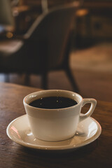 Hot coffee in white mug with dark backdrop. Freshly brewed coffee against black background. Cup of coffee on dark background.