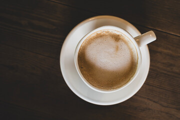 Hot latte coffee in white cup. Cappuccino style latte on table. Cup of latte with frothy milk. Freshly brewed latte with milk foam.