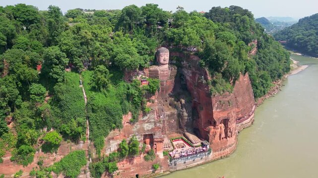 Leshan, China: Aerial orbit drone footage of the famous Leshan giant Buddha stone statue  at the confluence of the Min River and Dadu River in Sichuan in China.