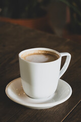Fototapeta premium Hot latte coffee in white cup. Cappuccino style latte on table. Cup of latte with frothy milk. Freshly brewed latte with milk foam.