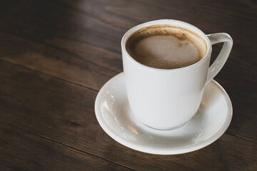 Hot latte coffee in white cup. Cappuccino style latte on table. Cup of latte with frothy milk. Freshly brewed latte with milk foam.
