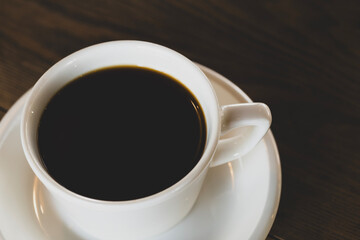 Hot coffee in white mug with dark backdrop. Freshly brewed coffee against black background. Cup of coffee on dark background.