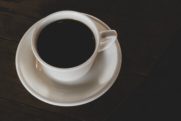 Hot coffee in white mug with dark backdrop. Freshly brewed coffee against black background. Cup of coffee on dark background.