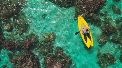 Woman happily paddle boarding in turquoise waters surrounded by vibrant coral reefs, perfect for adventure and relaxation on a summer vacation