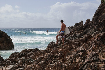 Obraz premium Surfer on the rocks, overlooking the sea and the horizon