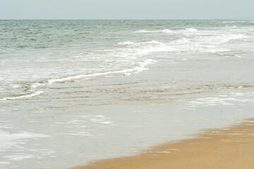 Gentle waves washing ashore on sandy beach on cloudy day