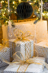A cozy concept for the Christmas holidays of 2026. Stylish gift boxes, toys, and a Christmas tree in the home interior of the living room. We are preparing gifts for our loved ones.