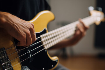 Obraz premium Musician plays a yellow bass guitar in a studio setting