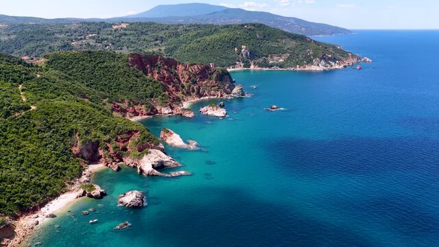 Aerial view of the beautiful coast of Mount Pelion, Greece, beach near Paltsi with emerald sea and red cliffs leading into emerald sea