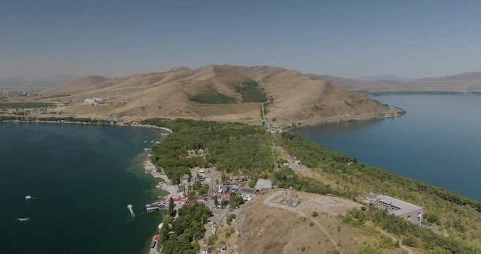 Aerial view of the peninsula jutting into the tranquil, blue waters of Lake Sevan, with a backdrop of rolling hills, Lake Sevan, Gegharkunik Province, Armenia.