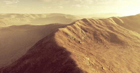 Warm sunlight casts long shadows over rolling desert hills. The arid terrain displays varying textures, emphasizing the natural beauty and tranquility of the landscape.
