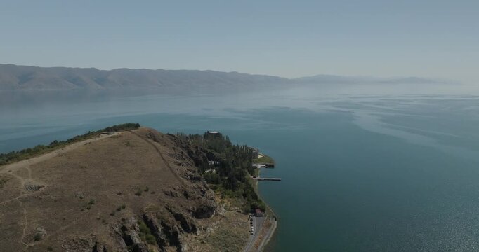 Aerial view of the peninsula with a path and trees jutting into the lake, contrasting with the vast expanse of water, Lake Sevan, Gegharkunik Province, Armenia.