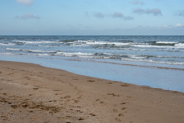 Waves gently rolling onto sandy beach on cloudy day