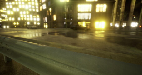 Brightly lit buildings line a city street at night, reflecting on the wet pavement. Cars pass by, creating a lively atmosphere in the urban environment.