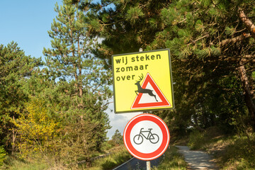 Deer crossing sign warning drivers in forest area with no bicycle allowed
