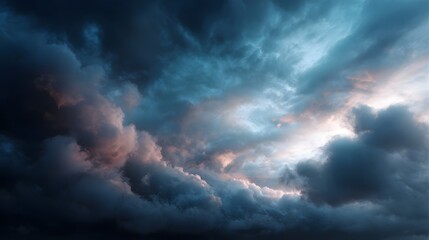 Obraz premium Dramatic cloudscape with dark rolling storm clouds illuminated by soft warm light breaking through the blue sky at twilight