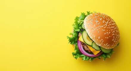 Burger with lettuce, onion, cheese and cucumber on yellow background