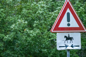 Warning sign indicating horse crossing and potential hazards