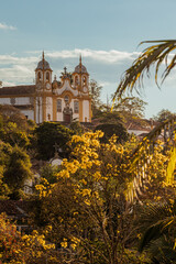 Dourado do fim de tarde com as árvores e construções em tons dourados com céu azul, Tiradentes,...