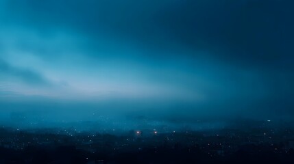 Naklejka premium Panoramic view of a city emerging from dense mist and fog at the tranquil blue hour with faint glowing lights illuminating the landscape