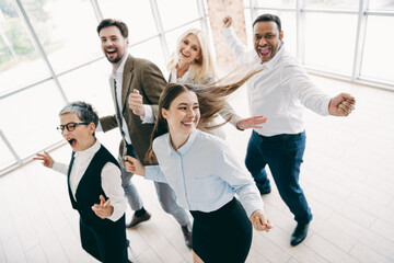 Group of colleagues joyfully celebrating together in a bright office environment, demonstrating...