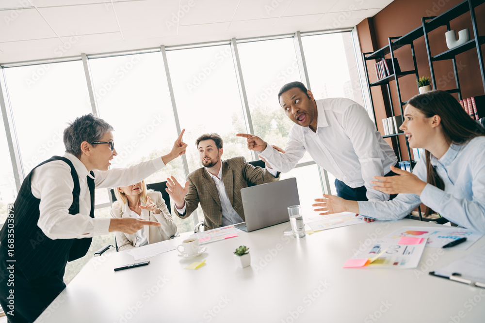 Poster office workers engaging in a lively team discussion around a meeting table in a modern workspace