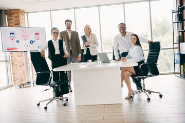 Group of professional coworkers collaborating in a modern office space with various tools and...