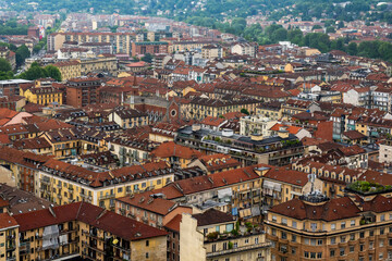 Fototapeta premium Dense residential cityscape of Torino, Italy with red tiled roofs and building structures in urban Italy.