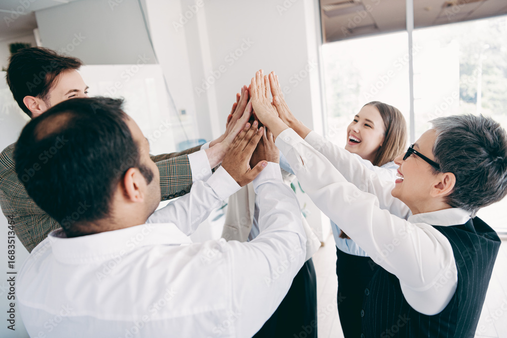 Aufkleber professional team celebrating success with a high-five in a modern office workspace displaying unity