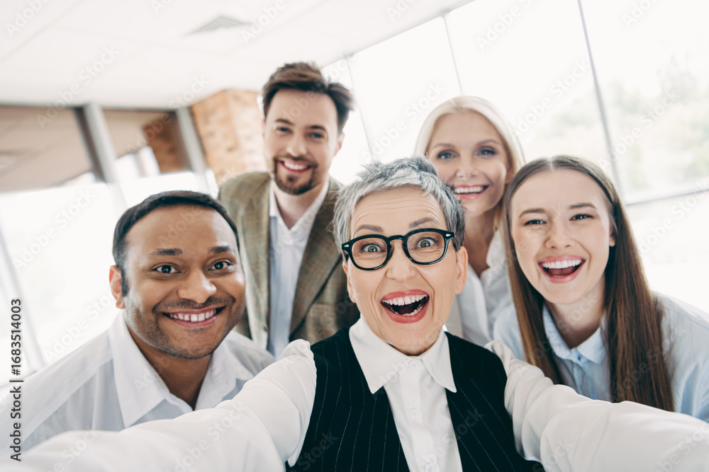 Aufkleber group of diverse colleagues joyfully taking a selfie in an office setting during a team-building eve