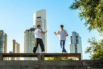 Two young men performing martial arts forms in a city setting