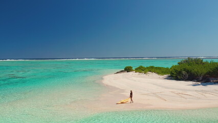 Aerial view of woman pulling kayak on turquoise lagoon beach in the tropics, creating a serene oasis for a relaxing vacation in paradise
