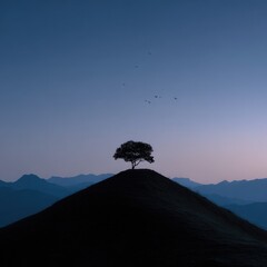 Solitary tree atop a hill under a twilight sky.  Silhouette of a single tree perched on a dark hilltop, against a hazy, dusky mountain range and a pale, twilight sky.  