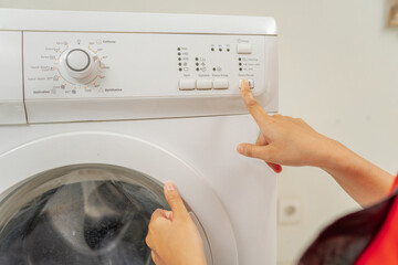 Here is a detailed closeup view of a person skillfully adjusting the settings on a washing machine