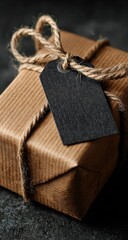 Close-up of a wrapped gift box.  A kraft paper-wrapped present is tied with natural twine, featuring a blank black tag. Dark background